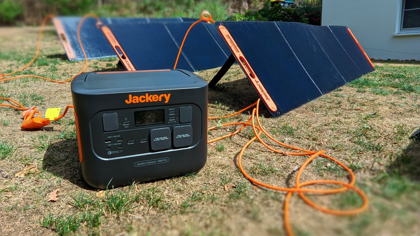 Mobiler Stromspeicher Jackery Explorer 1000 Pro in einem Garten. Im Hintergrund stehen passende Solarpanels zum Aufladen.