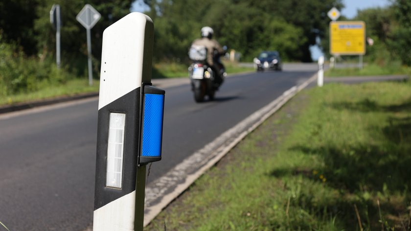 Blauer Reflektor am Leitpfosten an einer Landstrasse, Deutschland.