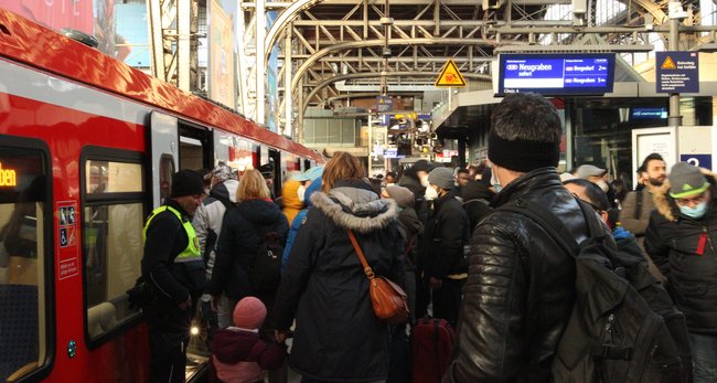 Eine rote S-Bahn steht am Bahnsteig, der voll mit Reisenden ist.