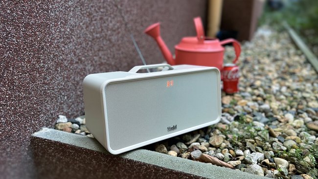 Bluetooth-Lautsprecher Teufel Boomster im Garten. Im Hintergrund eine rote Giesskanne und eine Dose Cola (Bildquelle: GIGA).
