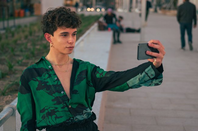 Eine Person in grünem Hemd fotografiert sich mit dem Smartphone.