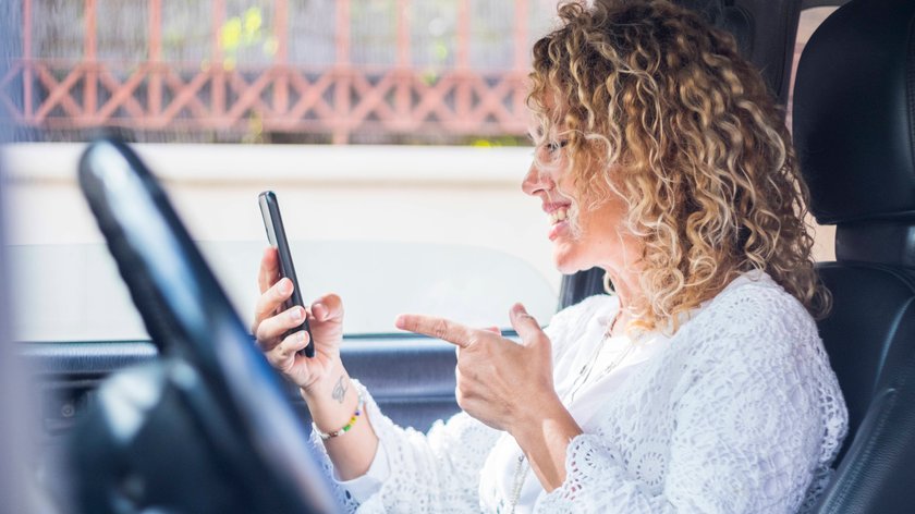 Eine blonde Frau tätigt einen Videoanruf im Auto.