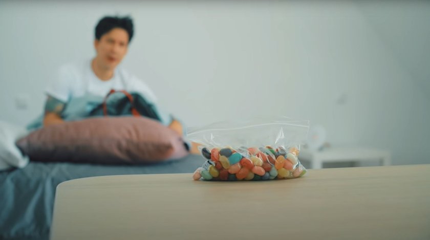 Auf einem Tisch liegt eine Tüte mit magischen Bohnen, im Hintergrund ist Julien Bam.