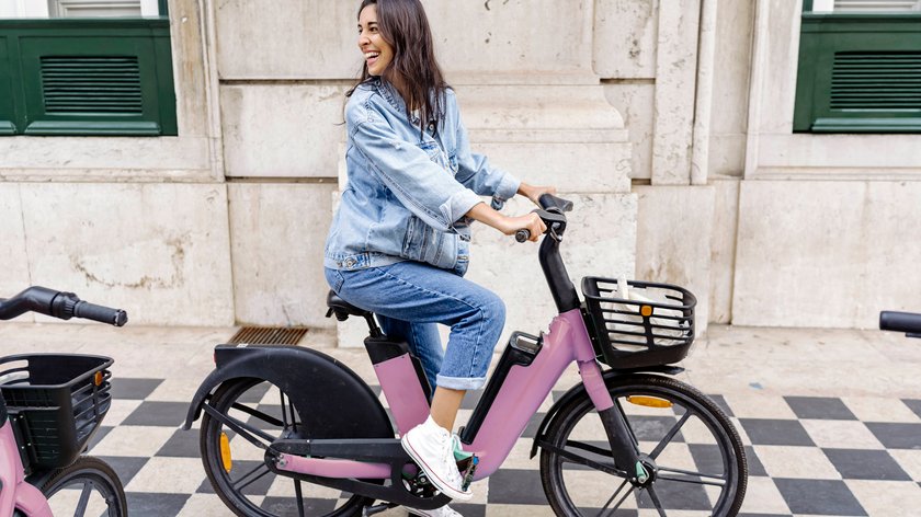 Eine Frau sitzt auf einem rosa E-Bike.