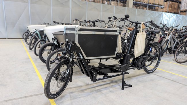 In einer Lagerhalle stehen Lasten-E-Bikes, dahinter normale E-Bikes.