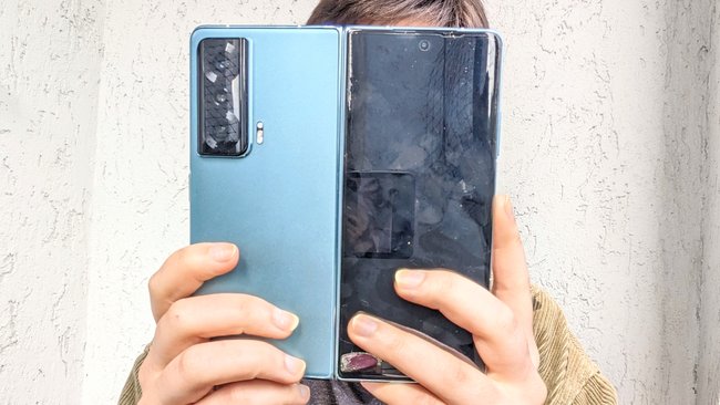 Eine Frau hält das Klapp-Smartphone Honor Magic Vs vor ihr Gesicht. Auf dem Außendisplay sind viele Fingerabdrücke zu sehen.