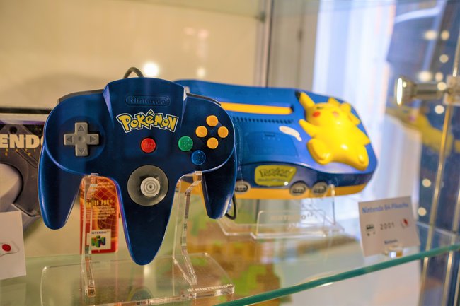 In einer Vitrine steht ein Nintendo 64 in der blaugelben Pikachu-Edition.