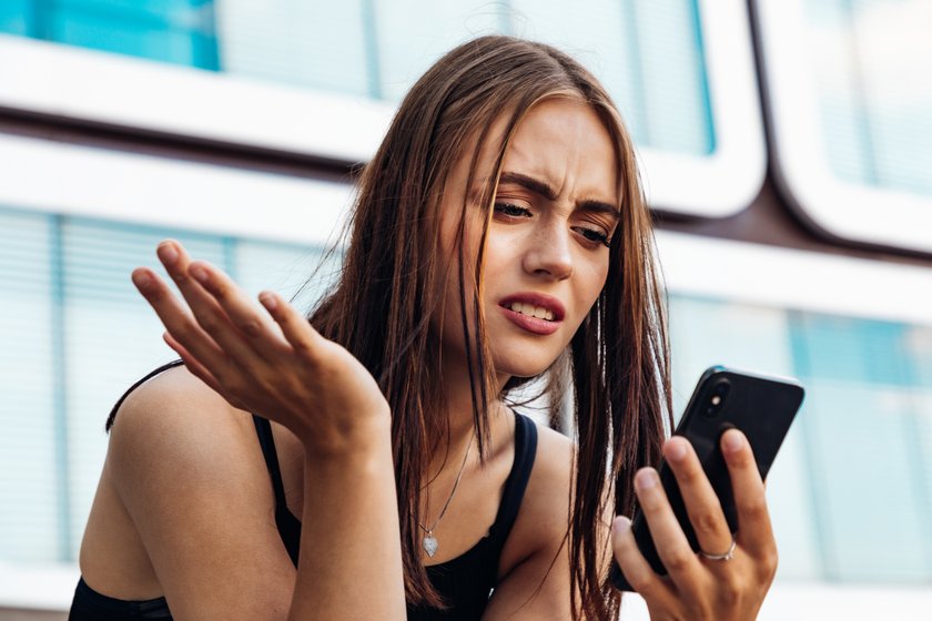 Frau schaut auf ihr Smartphone und ist empört.