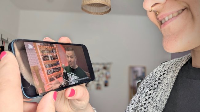 Eine Person hält ein iPhone 13 Mini in der Hand und schaut ein Video.