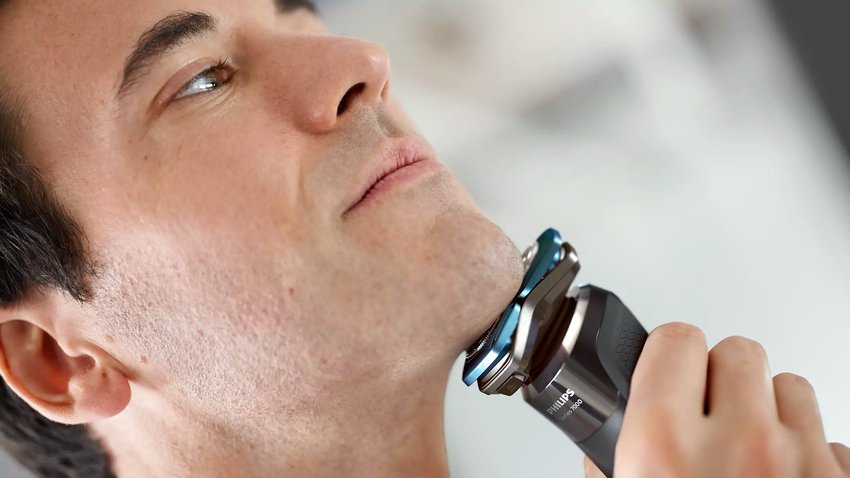 Ein Mann mittleren Alters rasiert sich mit einem Elektrorasierer am Kinn. Zu sehen ist das Modell Shaver Series 7000 von Philips (Bildquelle: Philips)
