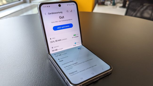 Auf einem schwarzen Tisch liegt das Samsung Galaxy Z Flip4. Eine Übersicht zum Akku ist auf dem Display geöffnet.