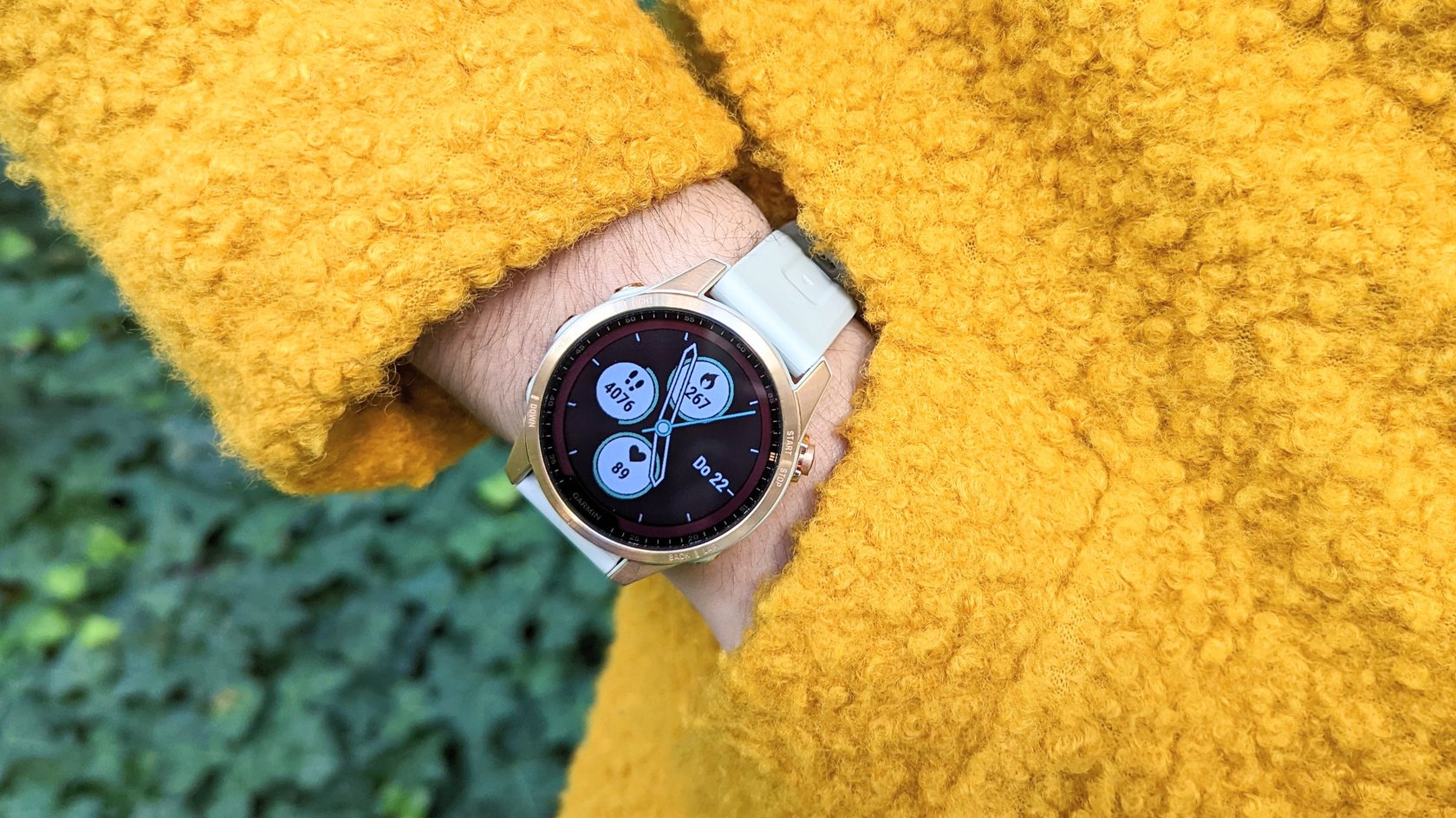 Ein gelber Mantel, eine Hand steckt in der Manteltasche. Am Handgelenk ist die Smartwatch Garmin Fenix 7S.