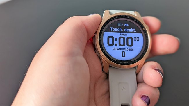 Eine Hand hält die Smartwatch Garmin Fenix 7S mit geöffneter Trainingsanzeige.