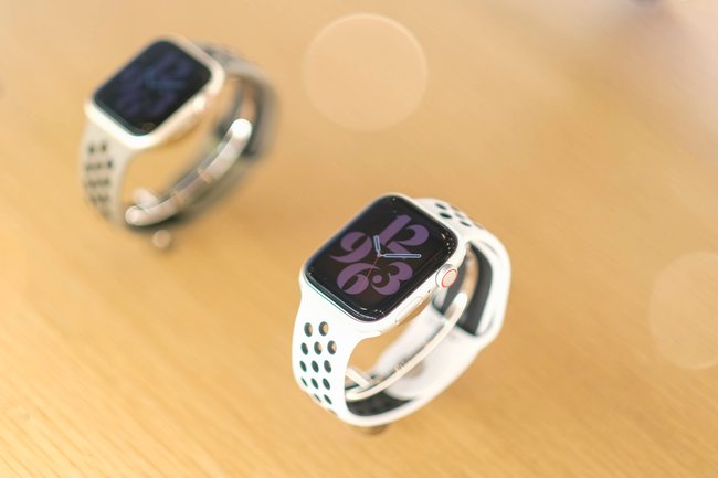 Auf einem Holztisch sind zwei Smartwatches aufgestellt. Es handelt sich jeweils um die Apple Watch Series 8.