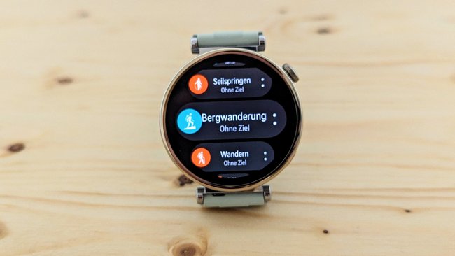 Die Huawei Watch GT 4 liegt auf einem Holzbrett, auf dem Display werden Sportarten angezeigt.