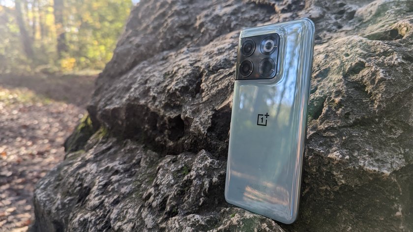 An einem Stein gelehnt steht das Smartphone OnePlus 10T, das eine mintgrüne Rückseite besitzt.