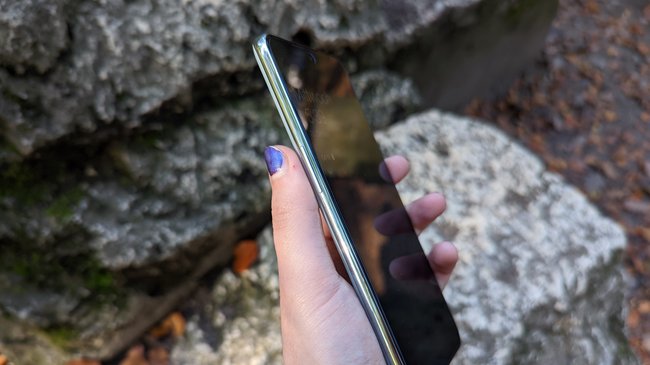 Eine Hand hält das Smartphone OnePlus 10T. Im Hintergrund sind Steine.