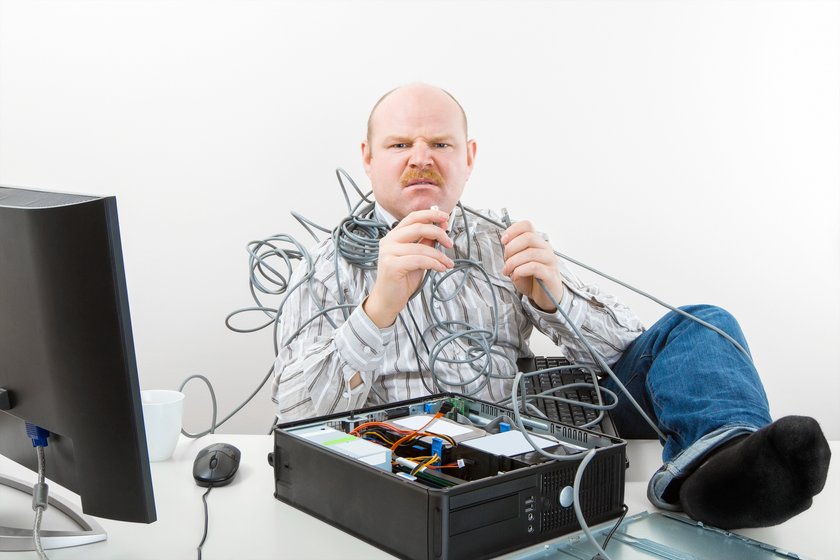 Portrait of furious businessman holding tangled cables of computer at desk in office Mod