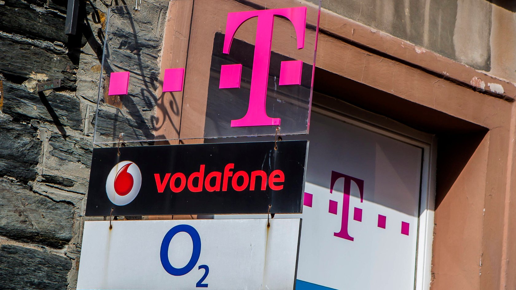 Schild mit Telekom-, Vodafone- und o2-Logos.