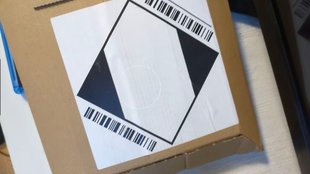 Amazon: Weißes Viereck mit schwarzen Dreiecken auf Paket – was bedeutet der Aufkleber?